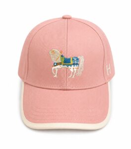 Pink baseball cap with a cream-colored brim and an embroidered white horse in blue harness on the front panel, plus an 'H' on the side.