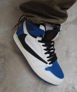 White and blue Air Jordan-style sneaker with a black swoosh, blue toe cap, and white midsection on a concrete floor,