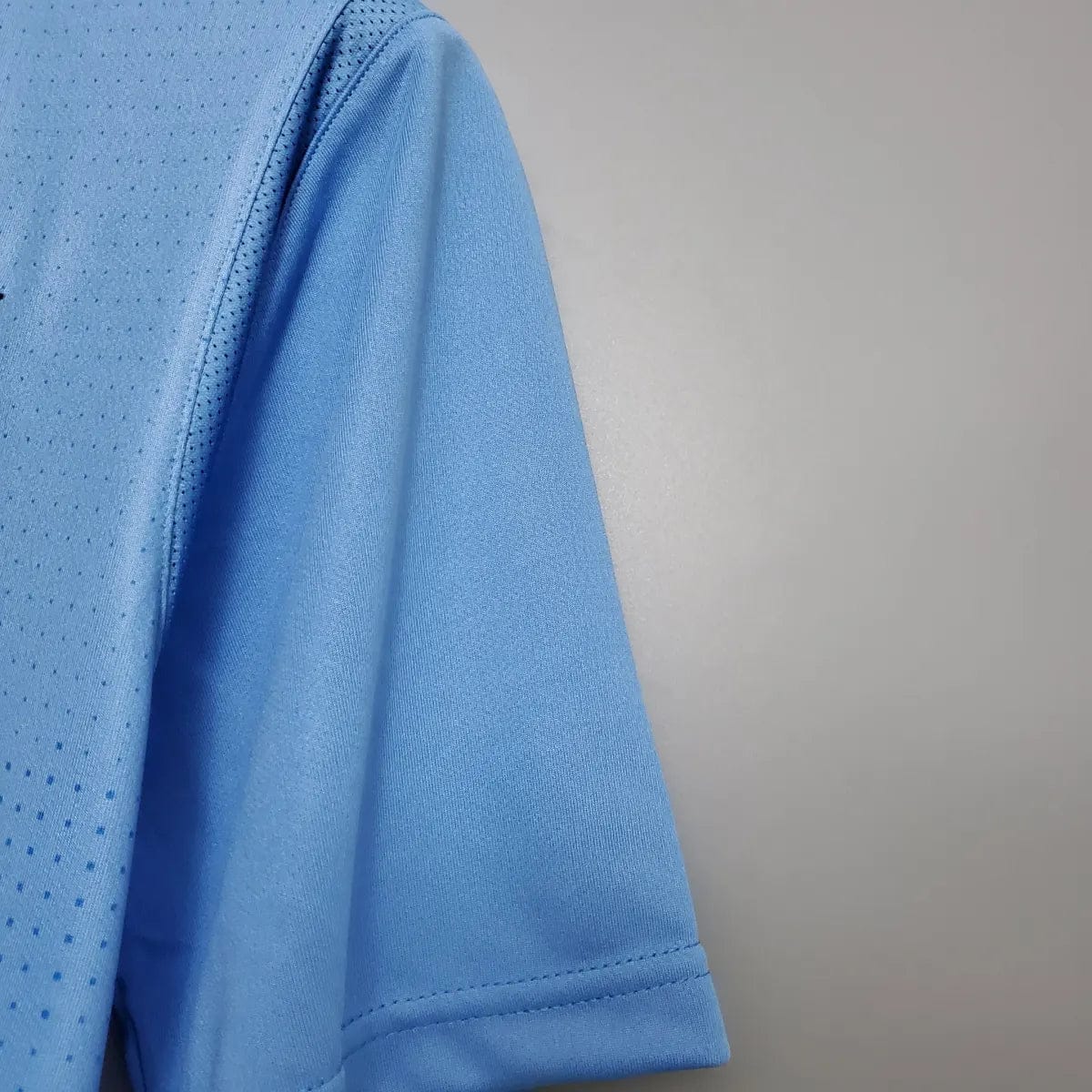 2012-Manchester-City-Retro-Home-Short-Sleeve-Jersey6 | UAE SPORT STORE Close-up of a light blue athletic jersey sleeve with a perforated mesh panel and stitched hem.