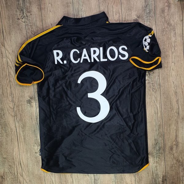 Black athletic jersey with yellow trim, displaying the name 'R. CARLOS' and number 3 on a wooden floor.