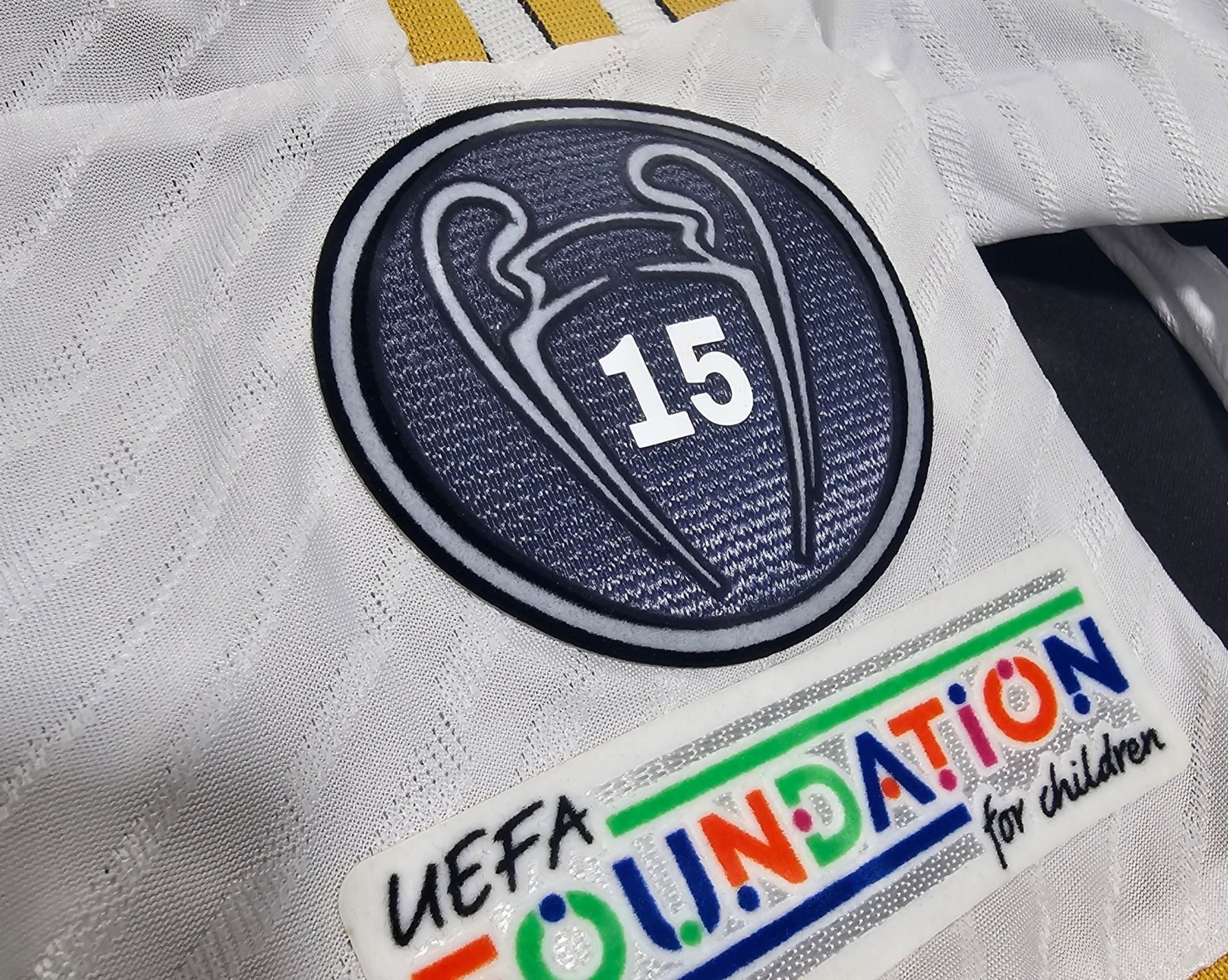 20240602-012745 | UAE SPORT STORE Close-up of a dark blue circular badge with the white number 15, resting on white textured fabric.