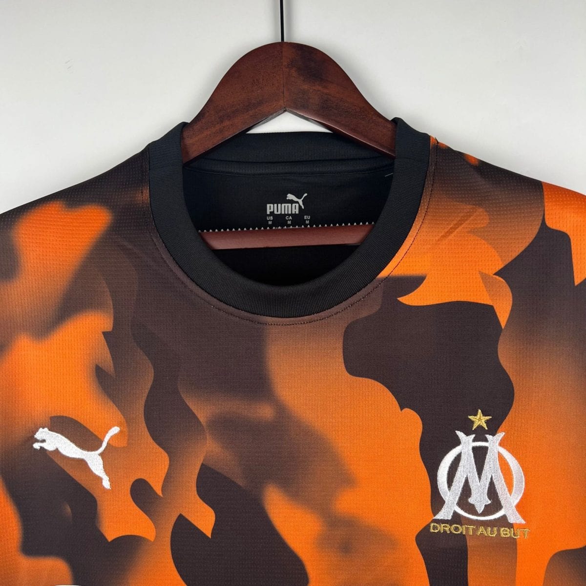 Orange camouflage sports jersey on a wooden hanger, Puma logo visible at the collar area