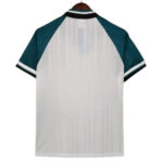 Back view of a white short-sleeve sports jersey with teal sleeves and striped collar, hanging on a wooden hanger