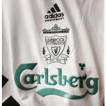 White athletic jersey featuring Adidas Equipment logo, Liverpool Football Club crest, and a prominent Carlsberg sponsor logo in green text.