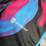 Close-up of black fabric with a blue-pink abstract design and the Aeroready logo with a small globe icon near it.