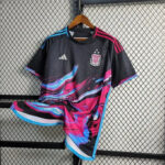 Black Argentina national team football jersey with pink and blue swirl design, hanging on a wooden hanger in front of a chain-link fence.