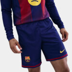 Person wearing FC Barcelona navy soccer shorts with red trim and club crest; yellow Nike logo visible on the leg.