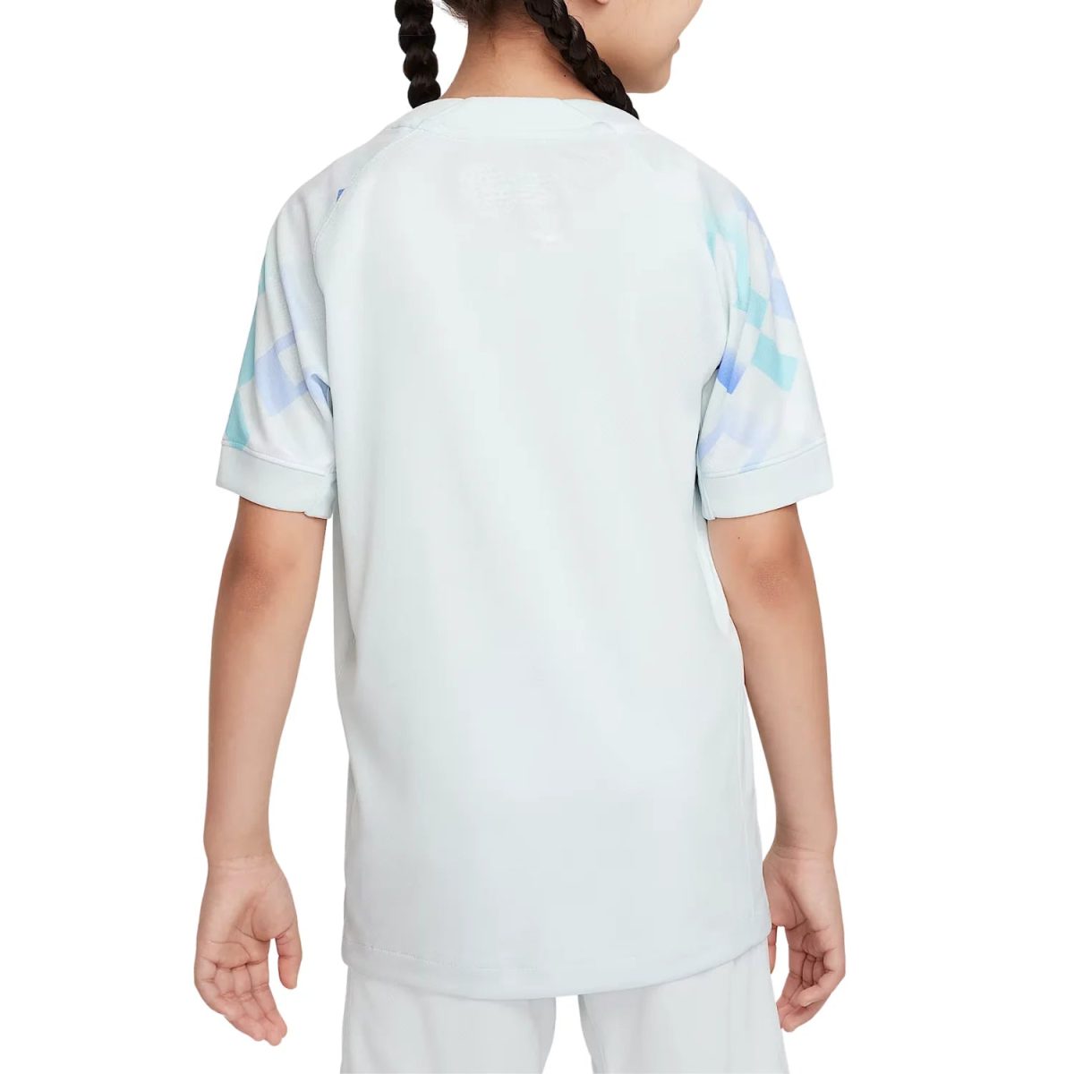 Back view of a child wearing a light pastel blue top with short sleeves and subtle geometric pastel-patterned panels on the sleeves.