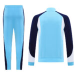 Light blue tracksuit with navy side panels and white sleeve accents, shown as a jacket and matching pants from the back/side view.
