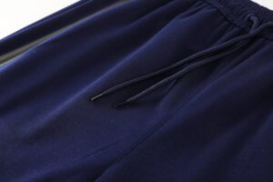 Close-up of navy blue athletic shorts or joggers fabric with a drawstring and elastic waistband detail, showing soft fleece-like material.