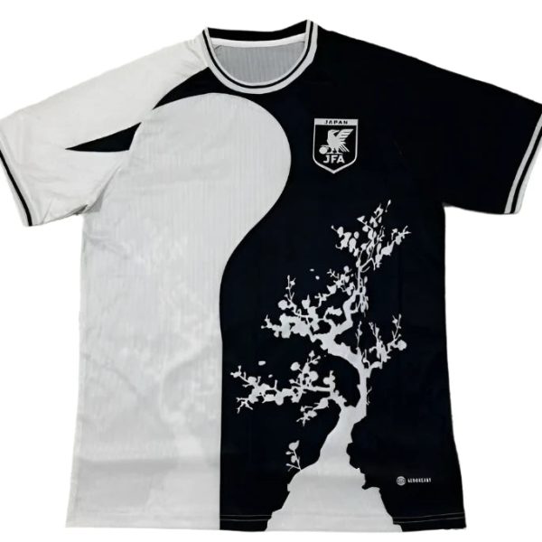 Split-color soccer jersey: white left, black right, featuring a white tree graphic on the dark side and a JFA crest on the chest area (Japan).