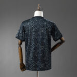 Back view of a black short-sleeve T-shirt with a light blue geometric abstract pattern on a dress form.