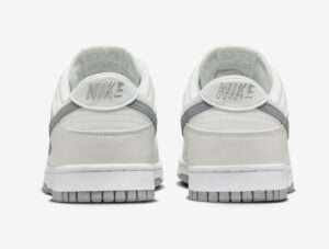 Rear view of a pair of white Nike sneakers with light gray accents and embroidered Nike logo on the heel tabs.