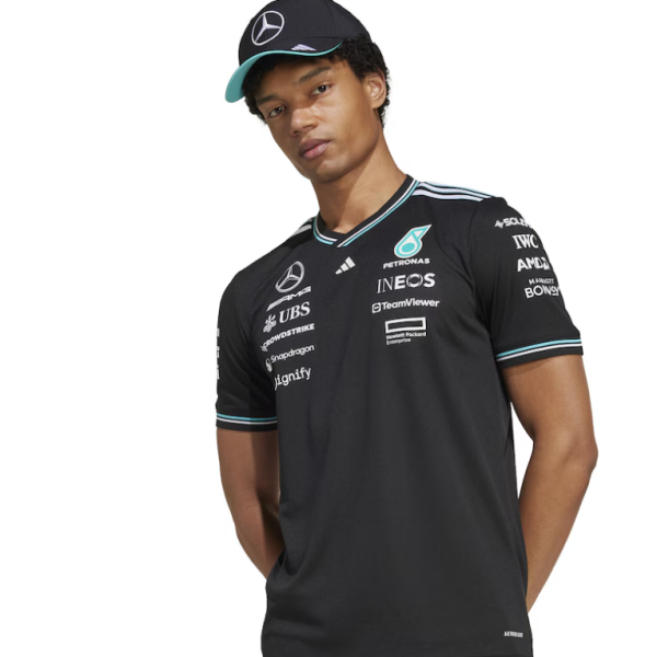 Young man in a black Mercedes team polo with sponsor logos and cap, looking slightly to the side.