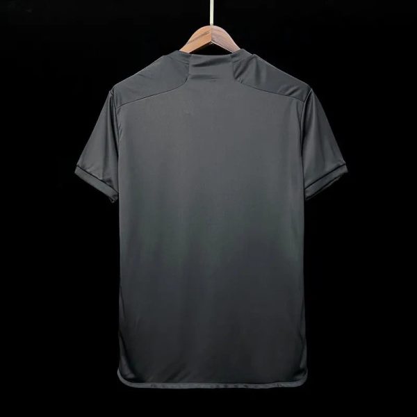 Dark gray short-sleeve polo shirt shown from the back, hanging on a wooden hanger against a black background.