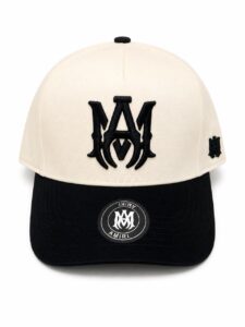 Beige crown and black brim baseball cap with a large black embroidered monogram on the front and a small side logo.
