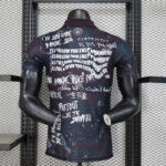 Back view of a dark graphic T-shirt on a mannequin, covered in white multilingual slogans and paint splatters.