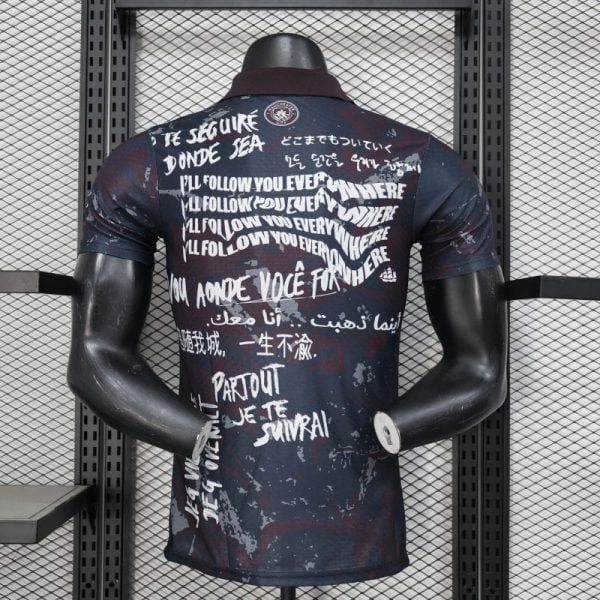 Back view of a dark graphic T-shirt on a mannequin, covered in white multilingual slogans and paint splatters.