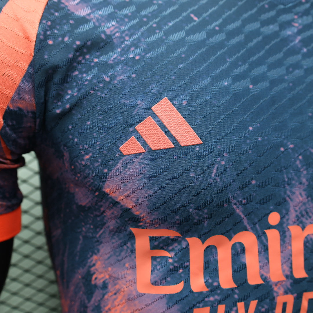 241b2f90 | UAE SPORT STORE Close-up of a blue patterned sports jersey featuring an orange Adidas logo and partial orange sponsor text.