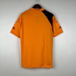 Orange short-sleeve shirt on a hanger, back view with a black shoulder panel.