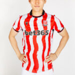 Person wearing a red and white striped soccer jersey with Bet365 sponsor, standing with hands on hips.