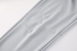 Light gray dress pants showing back welt pockets and a crease along the leg on a white background