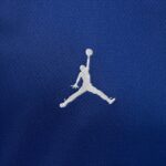 White Jumpman silhouette leaping with a ball on blue fabric background.