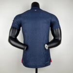 Back view of a navy blue cycling jersey on a mannequin, small French flag at the collar area.