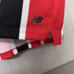 Close-up of red athletic fabric with the New Balance logo near the hem.