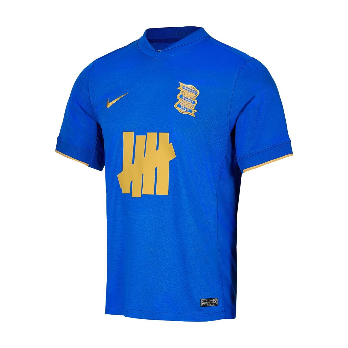 Blue football jersey with a gold Nike swoosh on the right chest and a gold crest on the left chest, featuring gold trim on the sleeves.