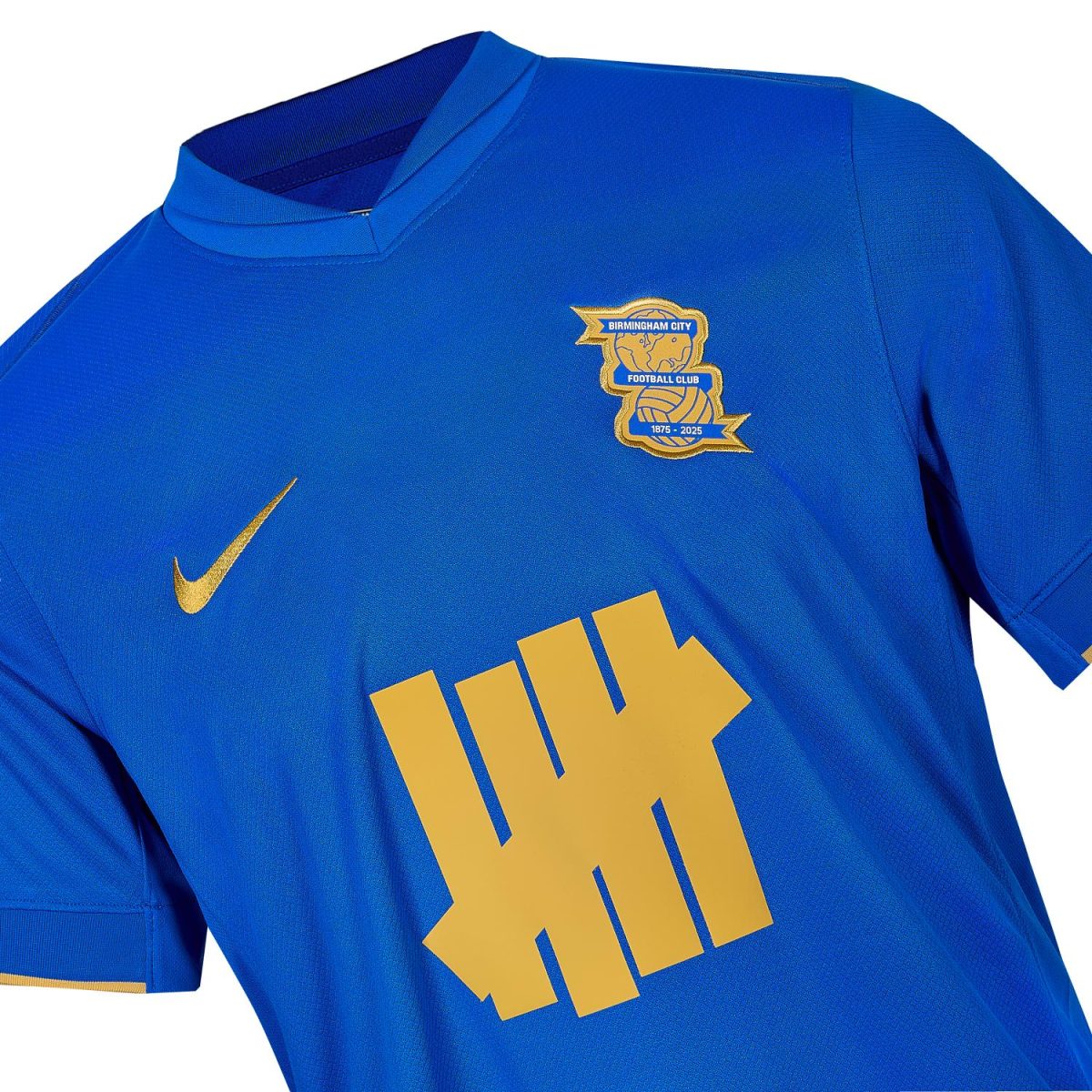 Blue Birmingham City football jersey with gold crest, gold Nike swoosh, and large gold graphic text on the front