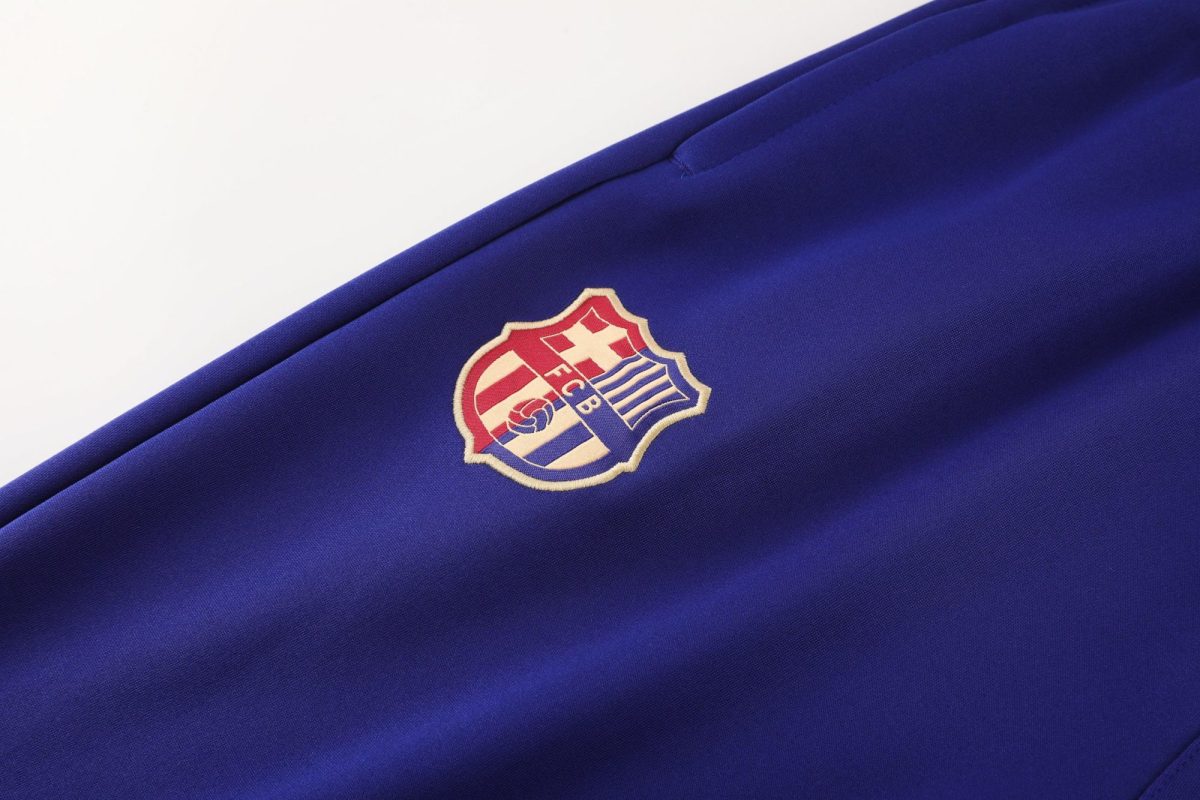Close-up of royal blue fabric with an embroidered shield emblem featuring red and white stripes and a blue field.