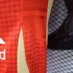 Close-up of bright red textured fabric with a diagonal beige panel and red strap.
