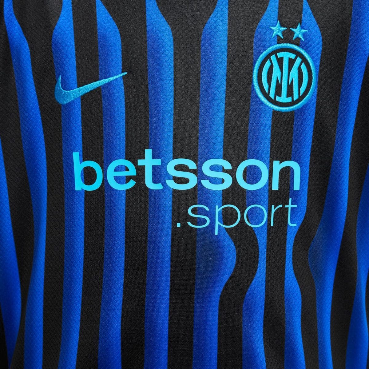 Close-up of an Inter Milan jersey showing blue-black stripes, Nike swoosh, crest, and Betsson sponsorship text.