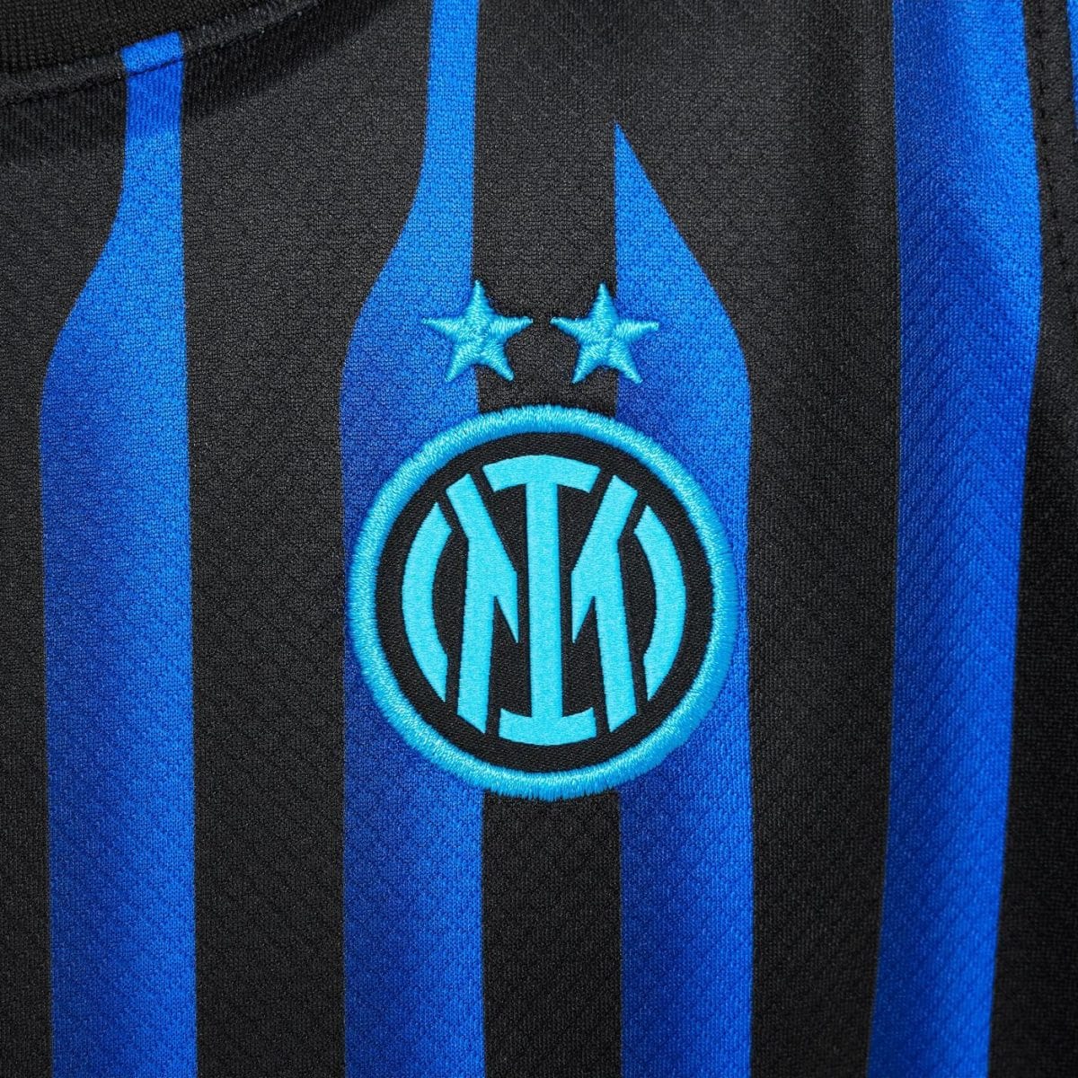 Close-up of an Inter Milan football jersey with blue and black vertical stripes and the club crest with two stars above it.