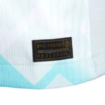Close-up of a black fabric label reading 'ENGINEERED' with a string of digits, stitched onto light blue patterned material.