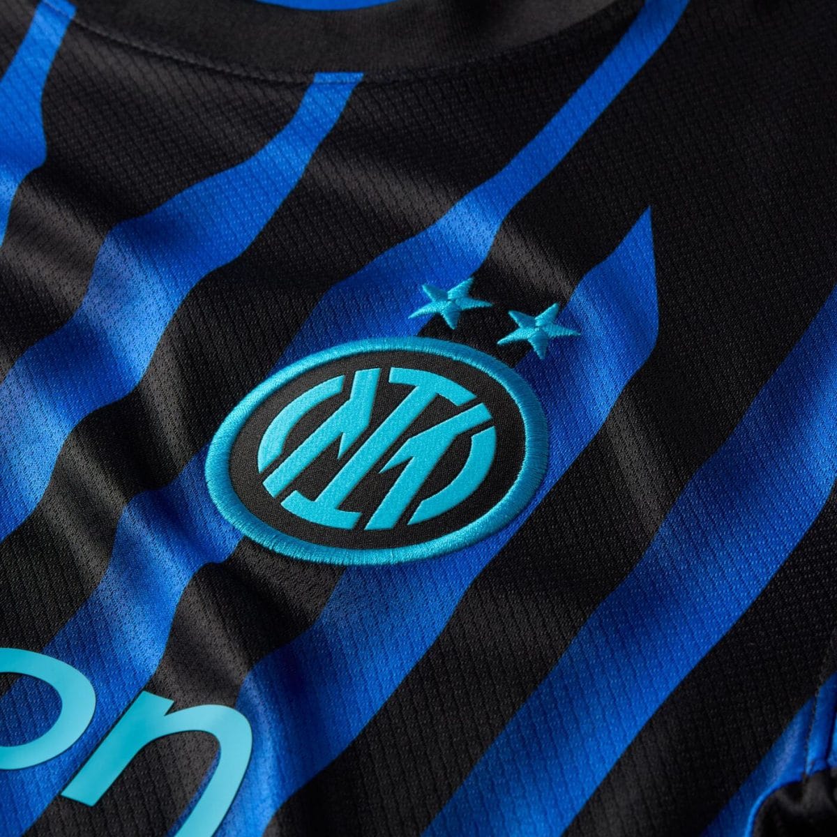 Close-up of an Inter Milan jersey showing blue-and-black stripes and the club crest with two stars above it.
