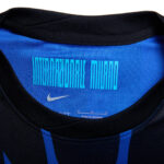 Blue jersey collar interior with a barcode-style print and a white Nike swoosh logo nearby.