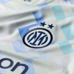 Close-up of a light blue and white fabric showing the Inter Milan crest with two stars above it on a patterned jersey.