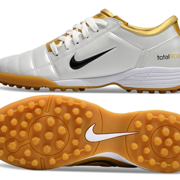 Nike Total 90 soccer boot, white upper with gold accents and black swoosh, orange outsole with studs (side view).