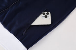 Navy jacket with a partially unzipped pocket revealing a white smartphone inside.