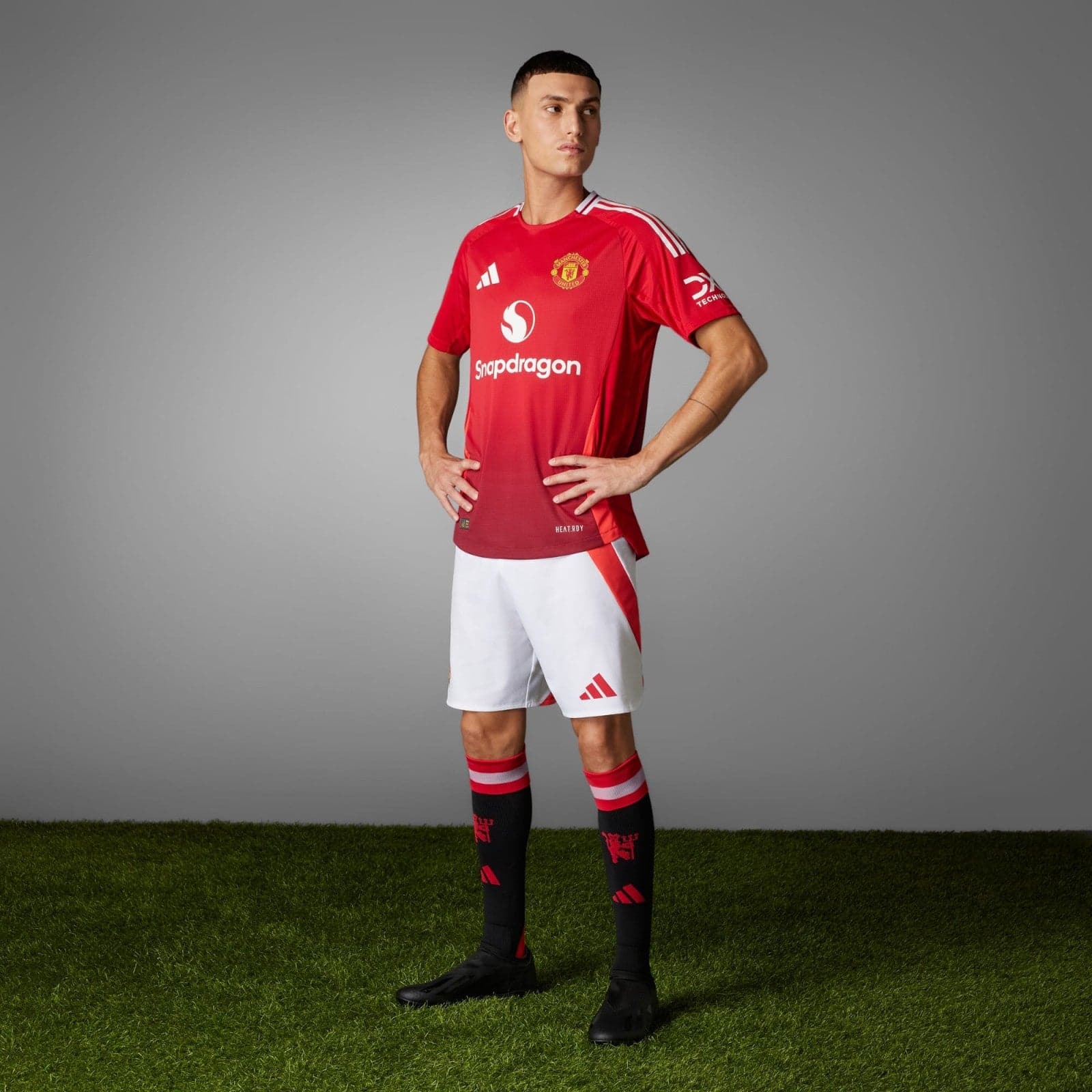 26Lcwu1p2P7pus1 | UAE SPORT STORE Male soccer player wearing a red Manchester United jersey, hands on hips, posing against a gray studio backdrop.