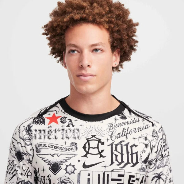 Young man with curly hair wearing a white graphic print T-shirt, facing slightly to the left.