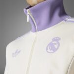 Close-up of a lavender zip-up collar on a white jacket, with a lavender Real Madrid crest on the chest.
