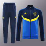 276df657 | UAE SPORT STORE Blue athletic tracksuit set: zip-up jacket with yellow chevron and matching navy pants with club crest and Adidas logo on chest/ thigh.