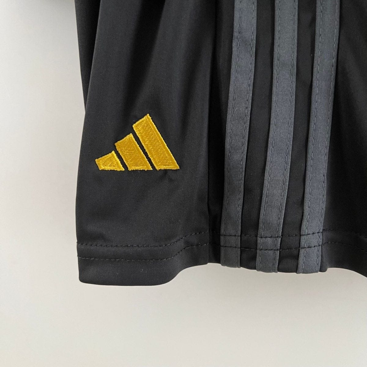 Close-up of a black fabric with three golden diagonal chevron stripes as an insignia on a garment.