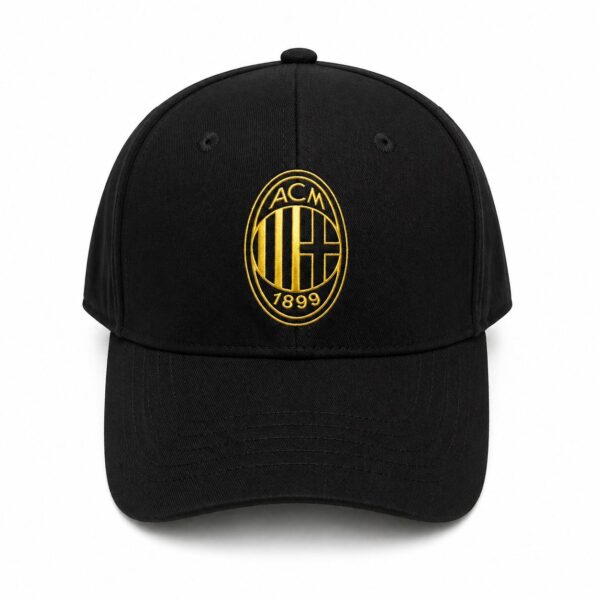 Black baseball cap with gold embroidered ACM 1899 crest on the front panel.