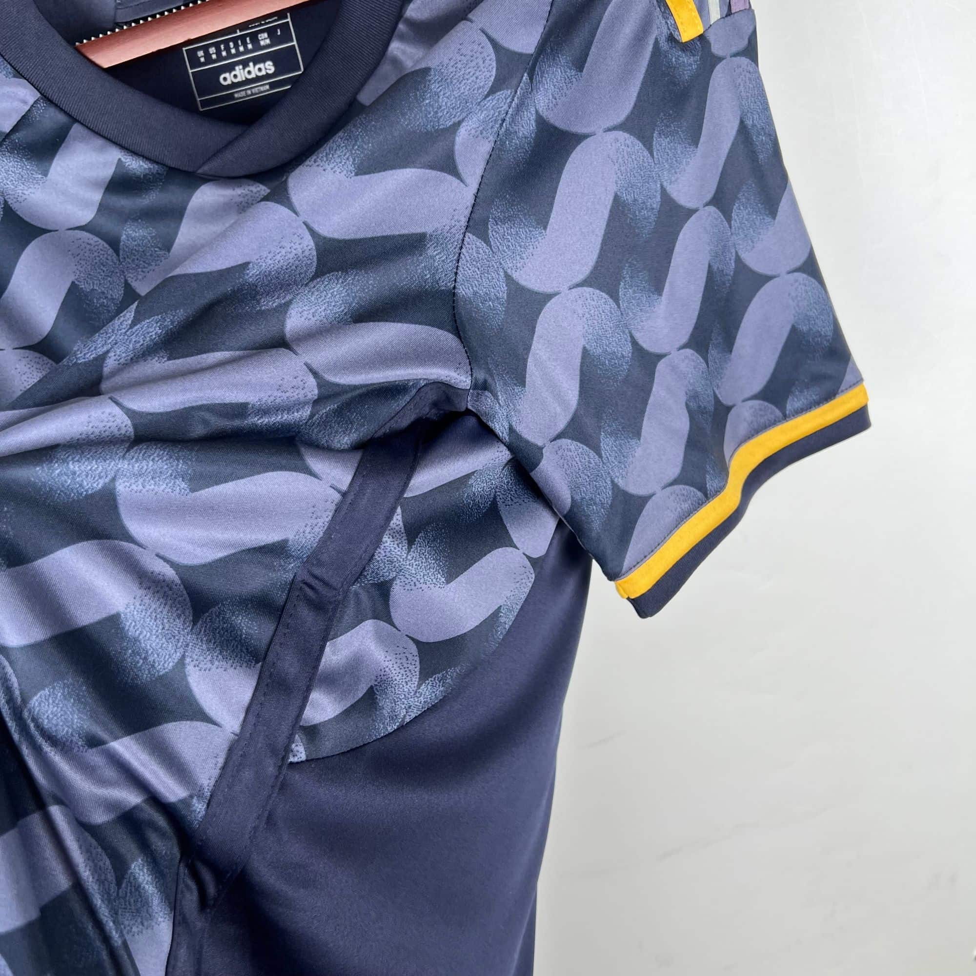 28b9ac63 | UAE SPORT STORE Close-up of a blue patterned Adidas jacket with yellow trim along the cuff and a label inside the neck area.