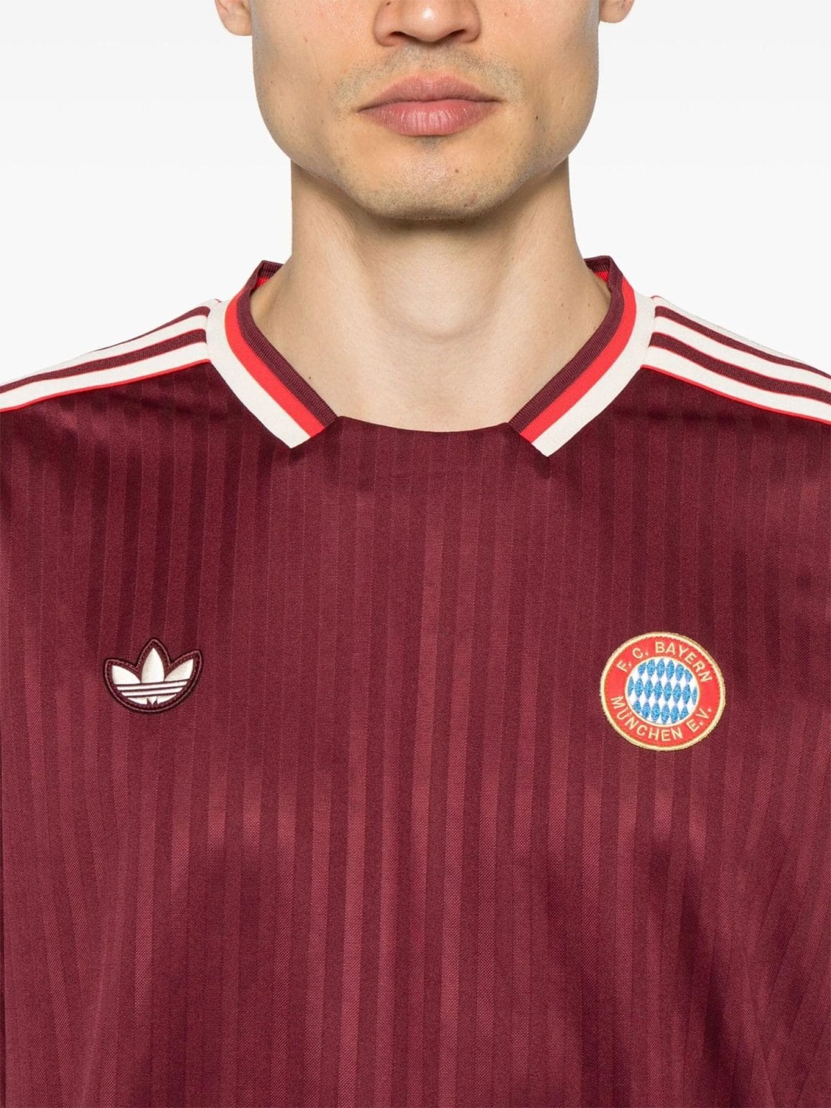 Close-up of a person wearing a maroon striped FC Bayern Munich jersey, showing the Adidas logo on the left chest area.
