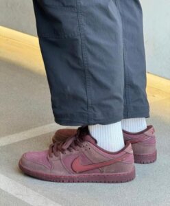 Burgundy Nike sneakers with white socks visible under navy cropped pants, standing on a concrete surface.